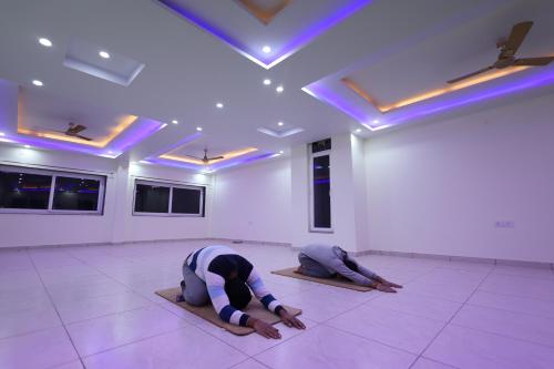 two people doing yoga in a room with purple lights at Perfectstayz Value Forest Valley Near Waterfall in Rishīkesh