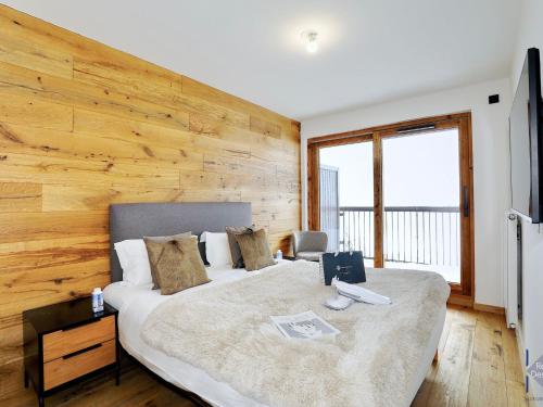 ein Schlafzimmer mit einem großen Bett und einer Holzwand in der Unterkunft Appartement Courchevel, 4 pièces, 6 personnes - FR-1-664-14 in Courchevel