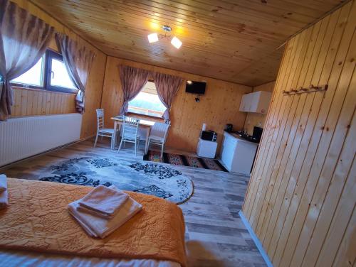 Habitación con cama, mesa y cocina. en Cabana doi mesteceni, en Drumu Carului
