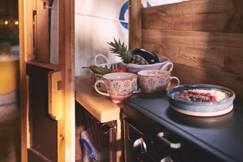 eine Küchentheke mit Tassen und einer Schale Obst in der Unterkunft Mushroom Yurt in Aberystwyth
