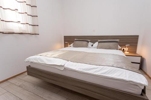 a bedroom with a large bed with a wooden headboard at Apartments Crnekovic Tomislava 8 in Baška