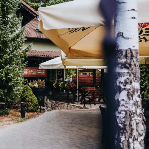 a yellow umbrella sitting on a tree in front of a restaurant at Domowa- Restauracja i Pokoje in Wielen Zaobrzanski