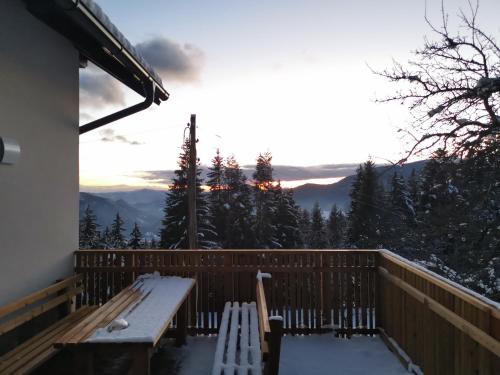 a bench on a deck with a view of the mountains at Cottage Planska koča in Vitanje