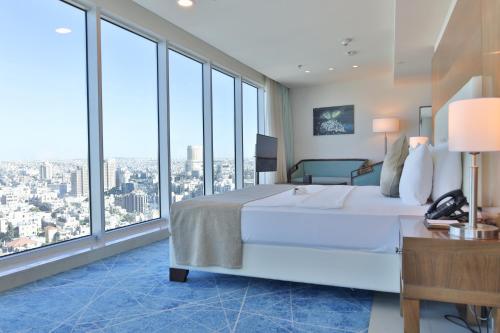 a bedroom with a large white bed and large windows at Coral Tower Hotel by Hansa in Amman