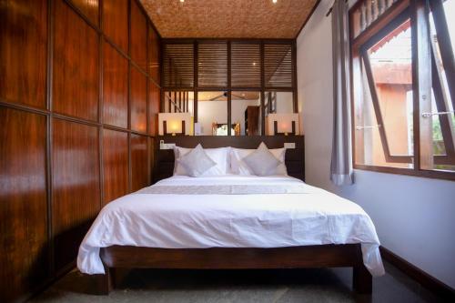 a bedroom with a large bed with a wooden wall at Gayatri in Ubud