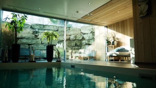 a swimming pool in a house with a stone wall at Hostellerie Le Petit Manoir in Morges