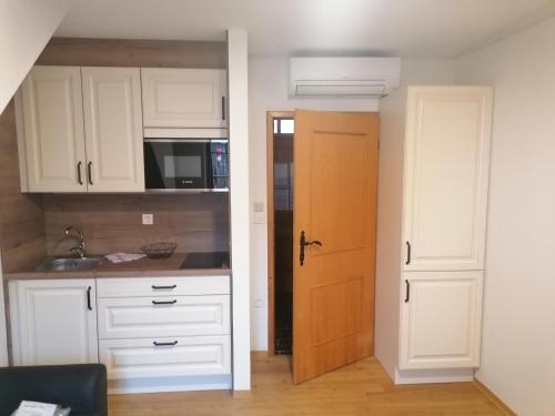 an open kitchen with white cabinets and a door at Apartments Prekmurska vas - Vital Resort in Moravske Toplice