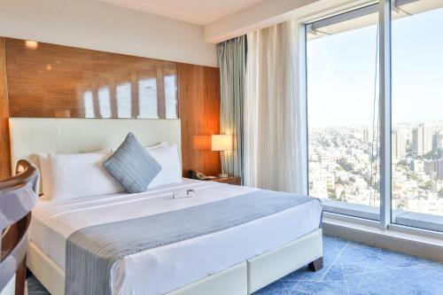 a hotel room with a bed and a large window at Coral Tower Hotel by Hansa in Amman