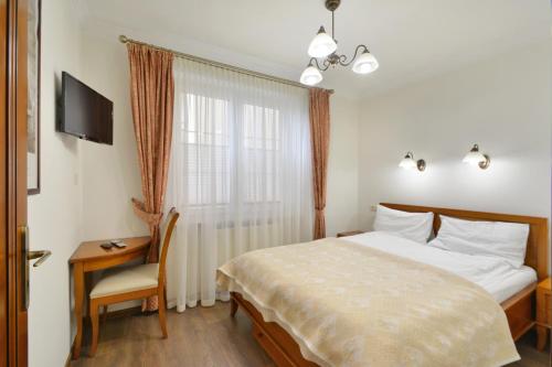 a bedroom with a bed and a desk and a television at NORTH Apartments Blue-Velvet, parking in Ustka