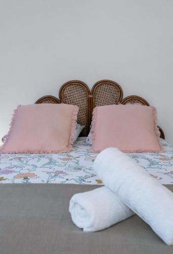 a bed with pink pillows and a white towel on it at Résidence Aristide Briand - Appartements en Centre Ville in Vichy