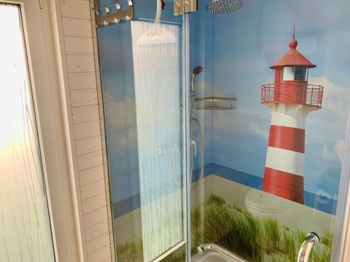 a shower with a glass door with a lighthouse painted on it at Hausboot Bali in Fehmarn