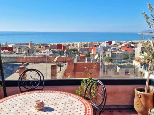 a table and chairs on a balcony with a view of a city at Auberge RIAD DLIM Tamraght in Tamraght Ouzdar