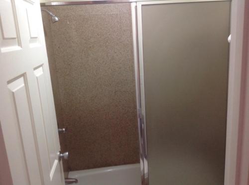 a shower with a glass door in a bathroom at Bronco Motel South Central in Los Angeles