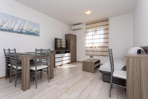 a living room with a dining room table and a bedroom at Apartments Crnekovic Tomislava 8 in Baška