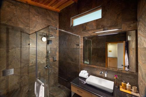 a bathroom with a shower and a sink and a mirror at Rakkh Resort, a member of Radisson Individuals Retreats in Pālampur