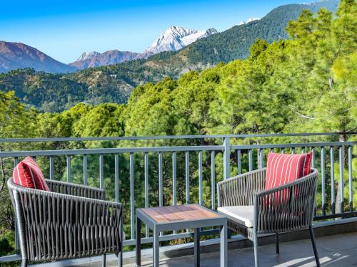 two chairs and a table on a balcony with mountains at Rakkh Resort, a member of Radisson Individuals Retreats in Pālampur