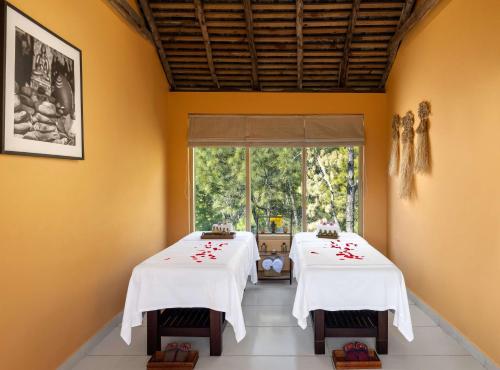 two dining tables in a room with a window at Rakkh Resort, a member of Radisson Individuals Retreats in Pālampur
