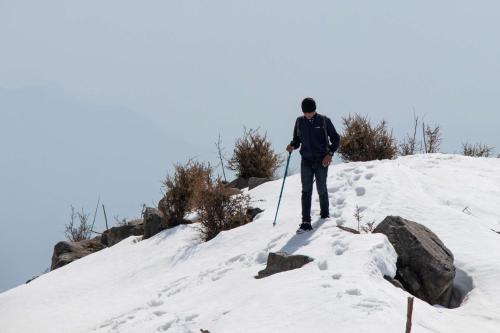 a man is walking up a snow covered slope at Rakkh Resort, a member of Radisson Individuals Retreats in Pālampur