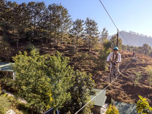 a man riding a bike on a zip line at Rakkh Resort, a member of Radisson Individuals Retreats in Pālampur