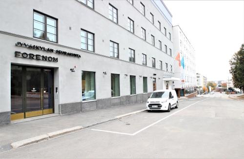 a white car parked in a parking lot in front of a building at Forenom Aparthotel Jyväskylä in Jyväskylä