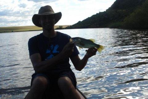 a man sitting in the water holding a fish at MacFarlanes in Harrismith