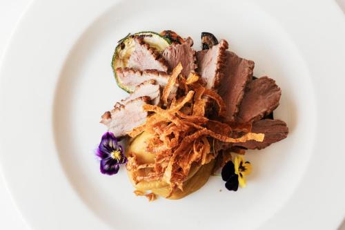 a plate of food with meat and flowers on it at Hotel Roma in Lisbon
