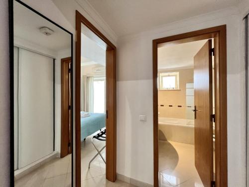 Albufeira Stylish by Homing في ألبوفيرا: غرفة مع مرآة وحمام مع حوض استحمام