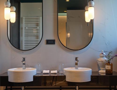two sinks in a bathroom with two mirrors at Palazzo Rainis Hotel & Spa - Small Luxury Hotel - Adults Only in Novigrad Istria