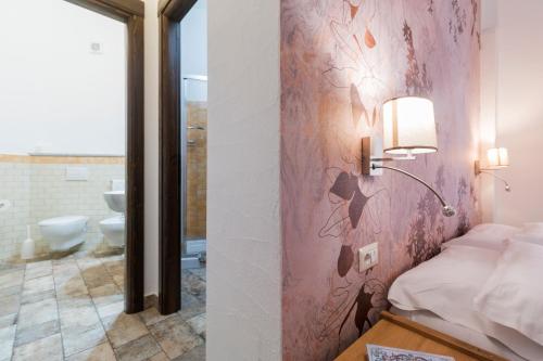 a bedroom with a pink wall with a bed and a bathroom at Karama in Dorgali