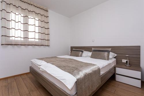 a bedroom with a large bed and a window at Apartments Crnekovic Tomislava 8 in Baška