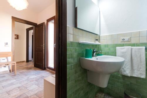 a green tiled bathroom with a sink and a mirror at Karama in Dorgali