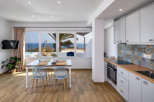 a kitchen with a table and chairs with a view of the ocean at Sonus Mare Beach Apartments, Vourvoulos Beach in Vourvoúlos