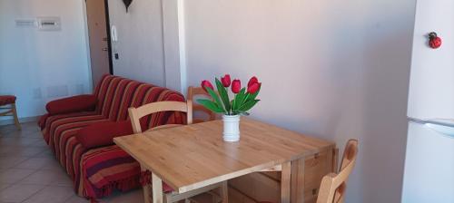 een tafel met een vaas met rode tulpen erop bij Casa Fiori di Arancio in Valledoria