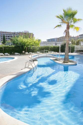 a swimming pool with a bridge and a palm tree at Rentalmar Royal in Salou