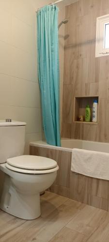 a bathroom with a toilet and a blue shower curtain at Hostal-Private Room Descanso y Relax in Puerto del Rosario