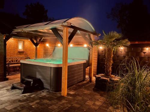 a hot tub with an umbrella in a backyard at night at Vakantiehuis de Heide in Bergen op Zoom