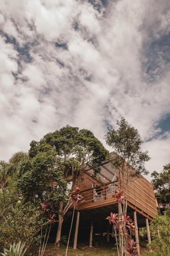 a house with a deck on a hill with trees at Pousada Colina Verde in Garopaba