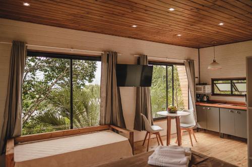 a bedroom with a bed and a table and a kitchen at Pousada Colina Verde in Garopaba