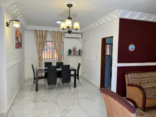 a dining room with a table and black chairs at Appartement New Stading YAOUNDE - MIMBOMAN MAETURE in Yaoundé
