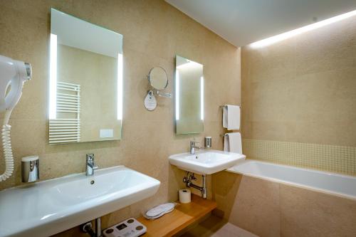 a bathroom with two sinks and a tub and a mirror at Eva Park Life & Spa in Konstancin-Jeziorna