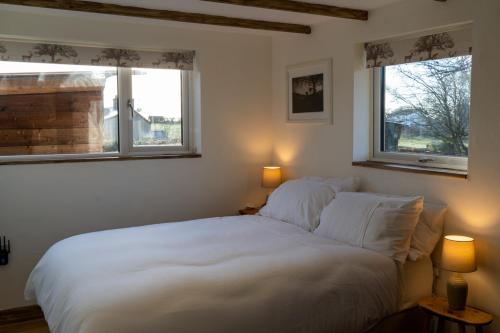 a bedroom with a large white bed with two windows at Rose Hideaway - Forest of Dean Cosy Cabin Retreat in Yorkley