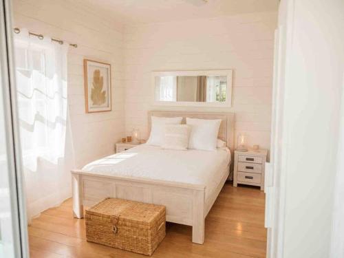 a bedroom with a white bed with a wooden floor at Driftwood Beach House in Kiama