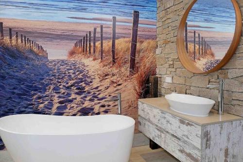 a bathroom with a bath tub and a painting of the beach at Driftwood Beach House in Kiama