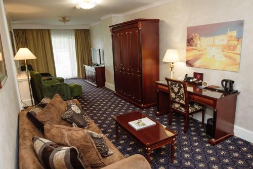 a living room with a couch and a desk in a hotel room at A Hoteli - Hotel Izvor in Arandjelovac