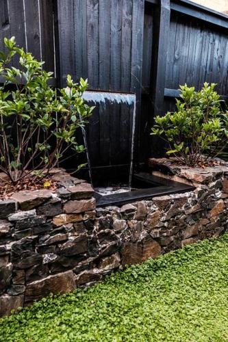 a stone wall with a water fountain in a yard at Driftwood Beach House in Kiama