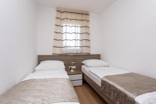 two beds in a small room with a window at Apartments Crnekovic Tomislava 8 in Baška