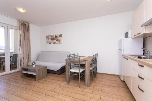 a kitchen and dining room with a table and a couch at Apartments Crnekovic Tomislava 8 in Baška
