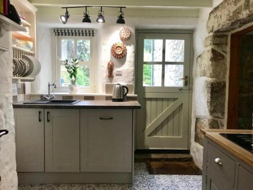 uma cozinha com uma porta, uma janela e um balcão em Dog friendly cottage with woodland & lake em Helston