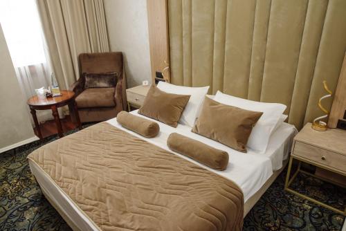 a bedroom with a large bed and a chair at A Hoteli - Hotel Izvor in Arandjelovac