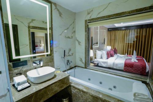 baño con lavabo, bañera y cama en The Grand Nirvana Hotel, en Bareilly